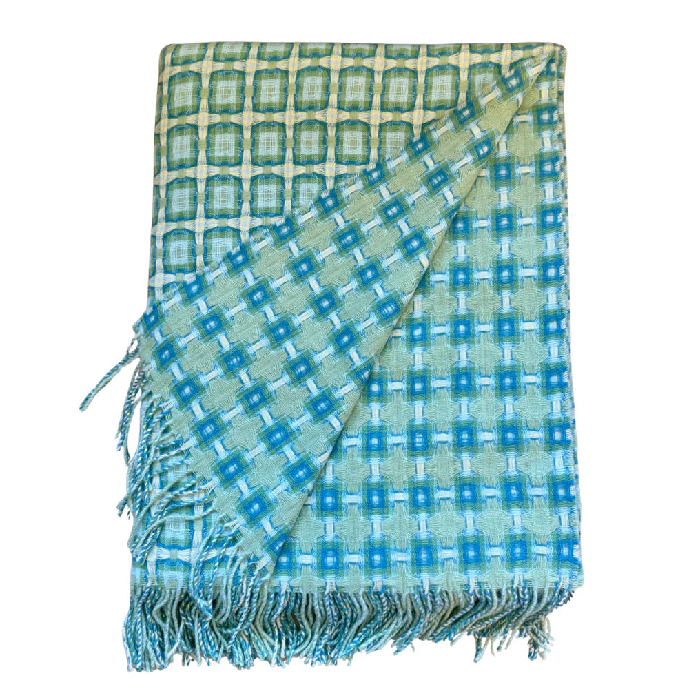 Woven throw blanket in sage green and teal with geometric square pattern and knotted fringe border on white background