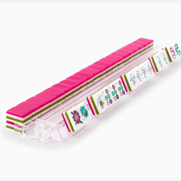 Pink acrylic mahjong tile set in clear case with floral and character tiles visible featuring green, pink, and teal designs