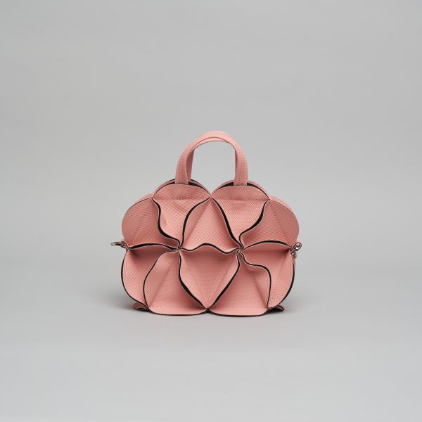 Rose pink leather handbag with sculptural petal-shaped panels outlined in black piping and silver chain shoulder strap