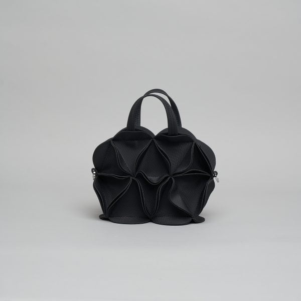 Black leather handbag with sculptural flower petal design, dual top handles and silver hardware on gray background