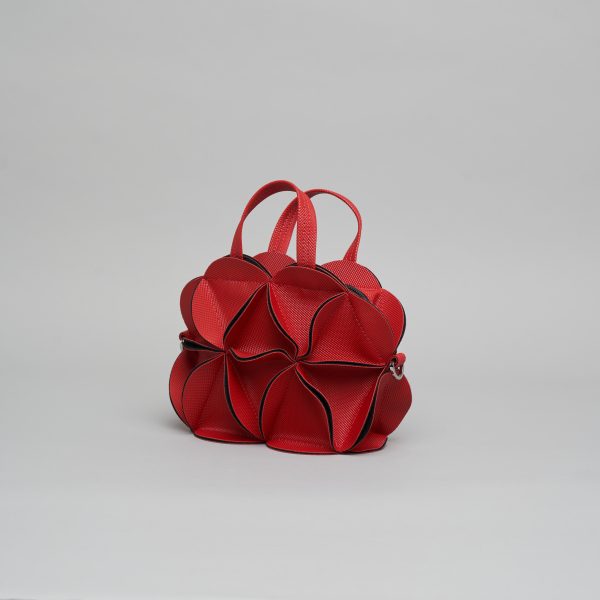 Sculptural red leather handbag with geometric petal-like panels forming organic rounded shape and single top handle