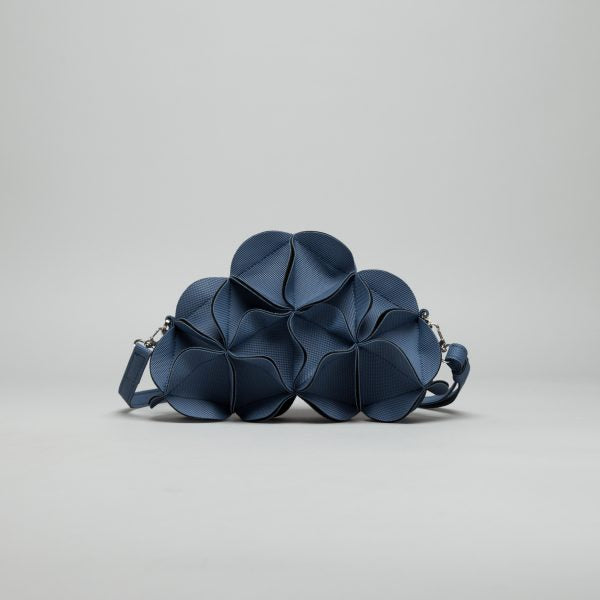 Navy blue leather sculptural handbag with geometric petal-shaped panels and adjustable chain shoulder strap