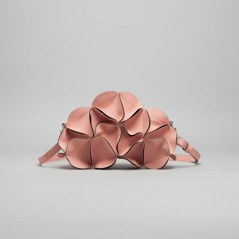 Rose gold leather crossbody bag shaped like clustered flower petals with dark burgundy piped edges and chain strap