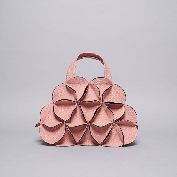 Blush pink geometric handbag with folded petal-like panels creating dimensional sculptural form and brown leather trim