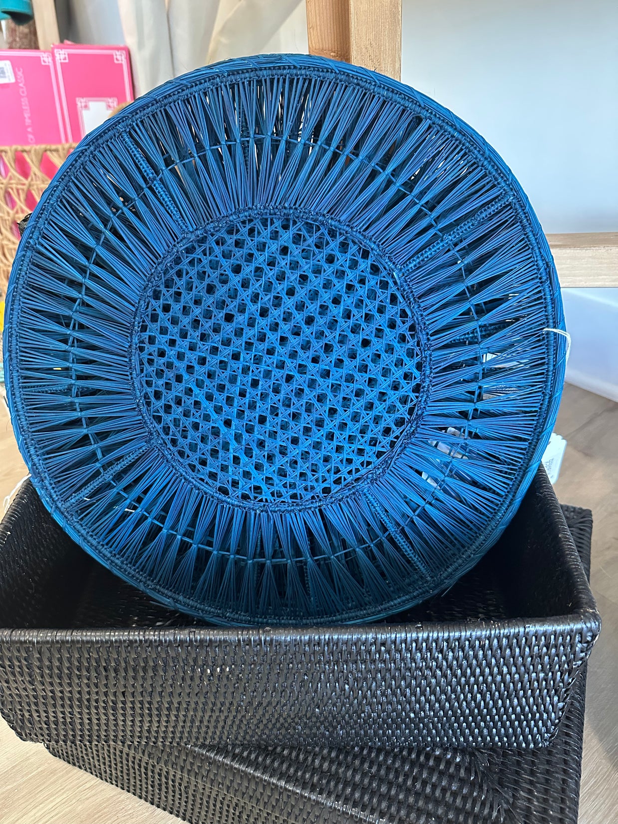 Cobalt blue woven wicker charger plate with radiating spoke pattern and lattice center on black woven storage box