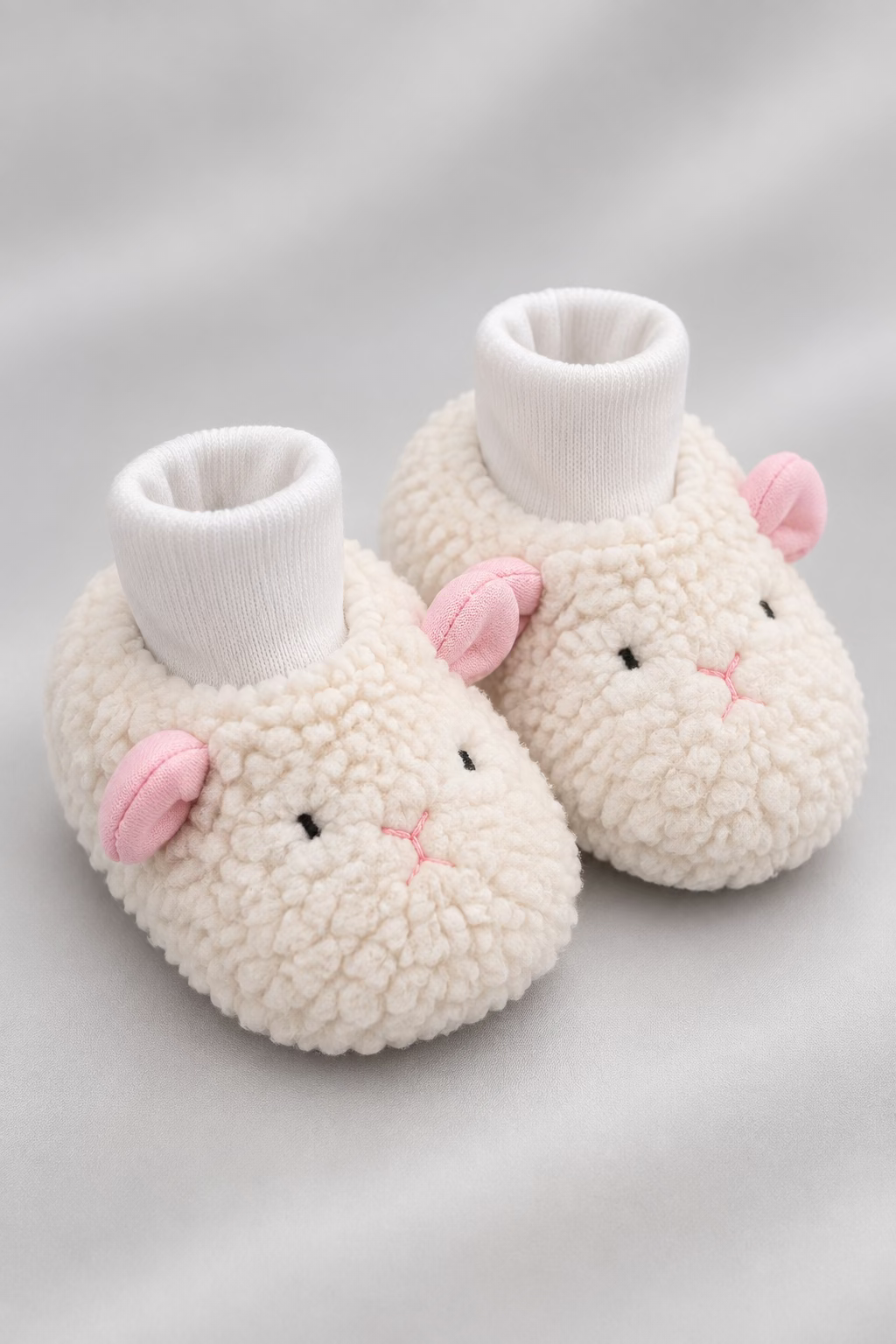Sheep-shaped slippers with fluffy texture on a light surface