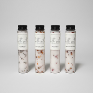 Four clear cylindrical bottles of bath salts with black caps and white labels. The labels read 'The Inspiration Haven' and 'bath salts' with variants Calming, Positive Energy, Self Love, and Dream Chaser.