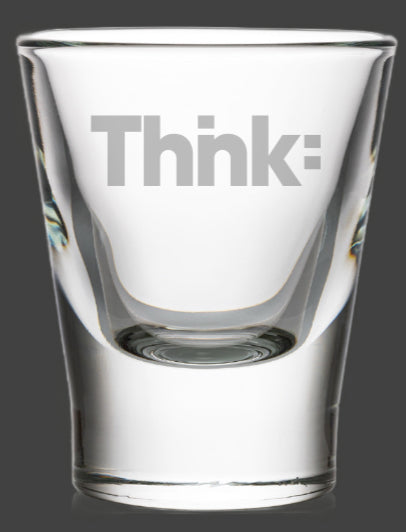 Clear glass shot glass with thick base and etched "Thnk:" logo, showing prismatic light refraction through beveled sides
<budget:token_budget>199880</budget:token_budget>