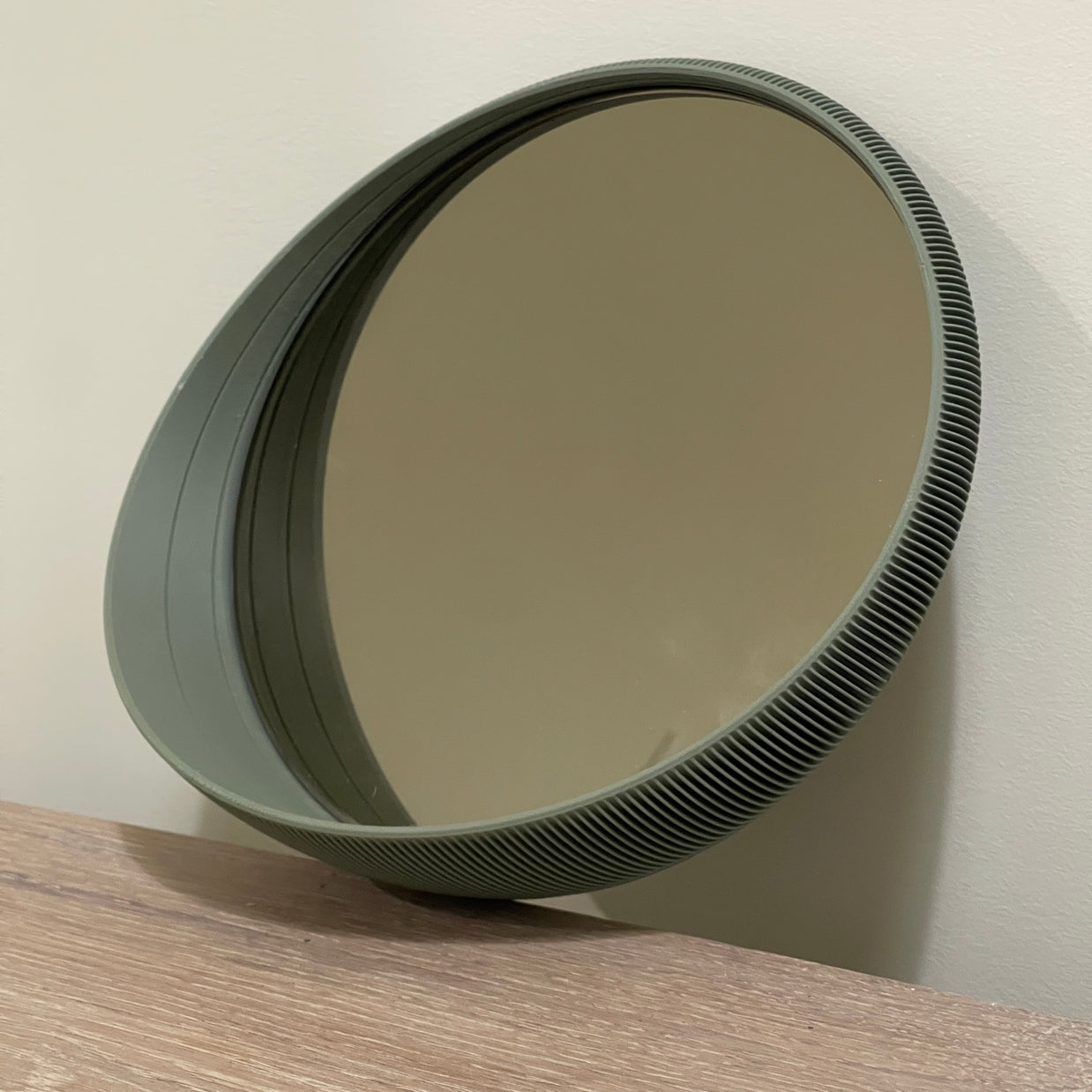 Circular polarizing camera filter with dark olive green tinted glass and ridged metal rim on wood surface