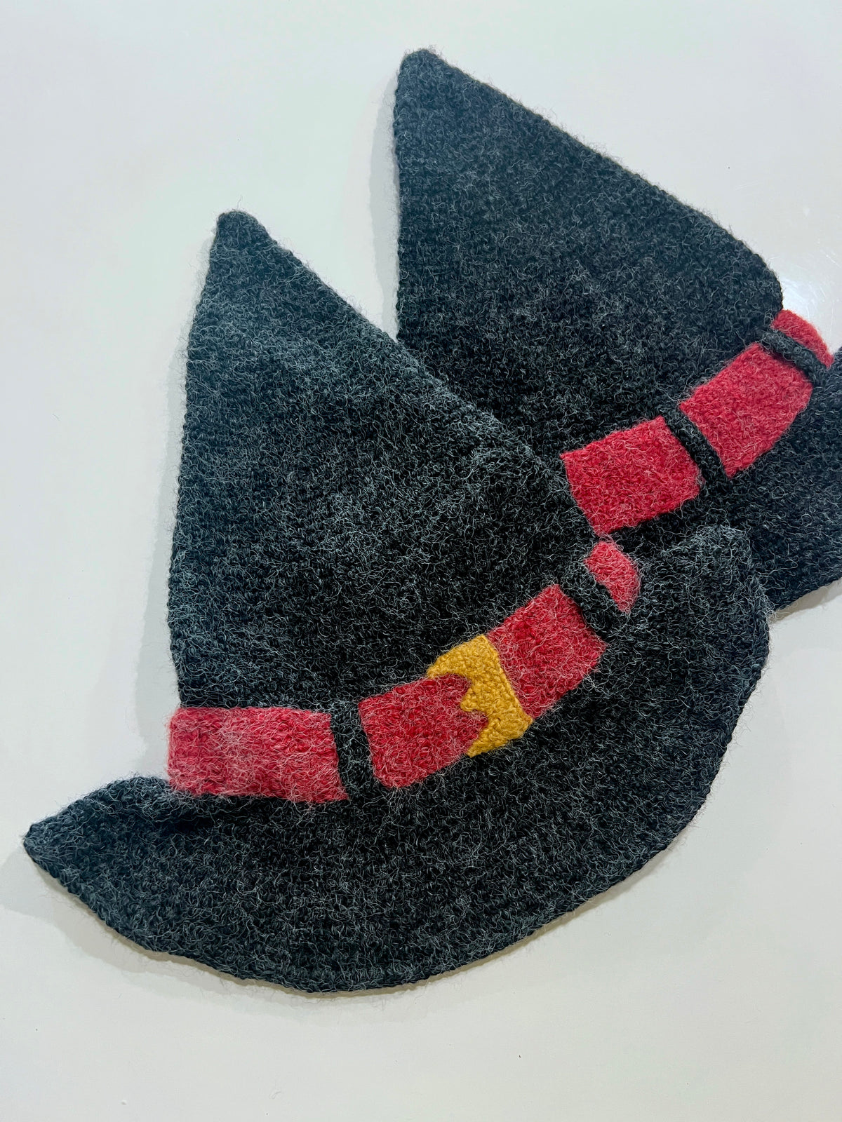 Black textured doormat shaped like cat silhouette with pointed ears and red collar with yellow bell detail