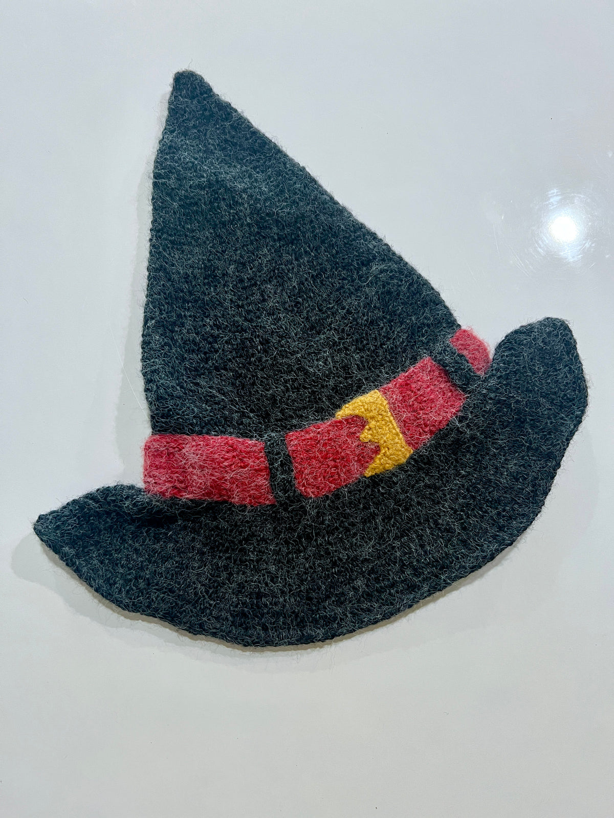 Black felt witch hat decoration with red hatband featuring yellow square buckle and upturned brim