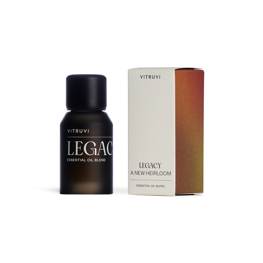 Matte black frosted glass essential oil bottle with black cap beside cream and rust ombre gradient cardboard box labeled Legacy