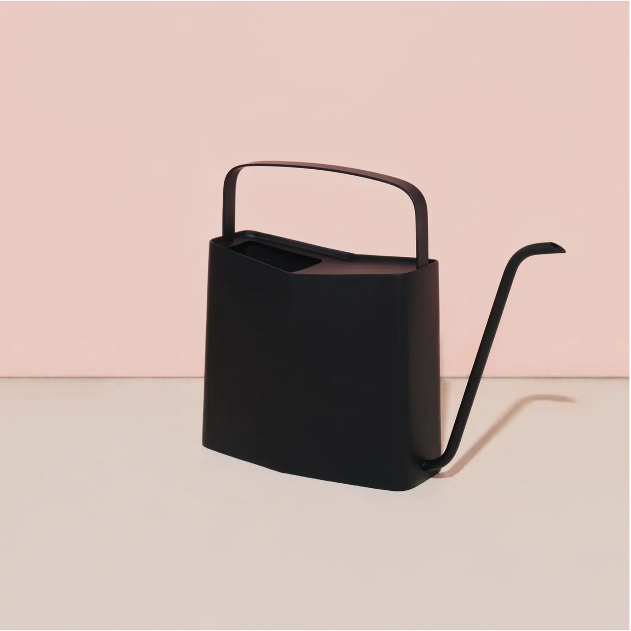 Matte black metal watering can with curved spout and arched top handle in modern minimalist design