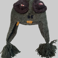 Gray knit monster aviator hat with brown goggle detail, orange bow tie, braided ear flaps with yarn tassels