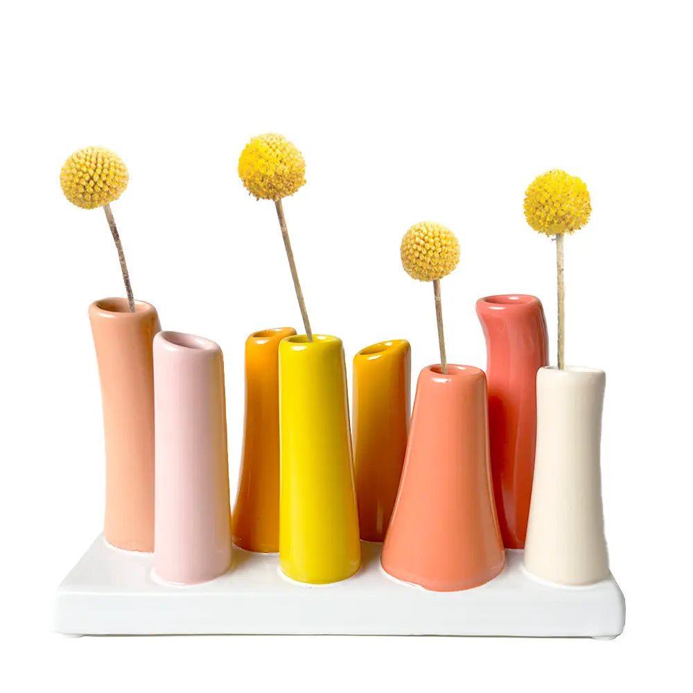 Multi-tube ceramic bud vase set on white tray in peach, pink, mustard, yellow, coral, and cream with dried billy balls