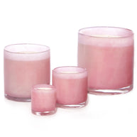 Set of four pink frosted glass cylinder candles in varying heights with lit wicks and clear glass bases