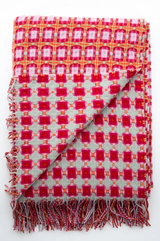 Woven cotton throw blanket with bold pink grid pattern on white background and multicolored knotted fringe trim