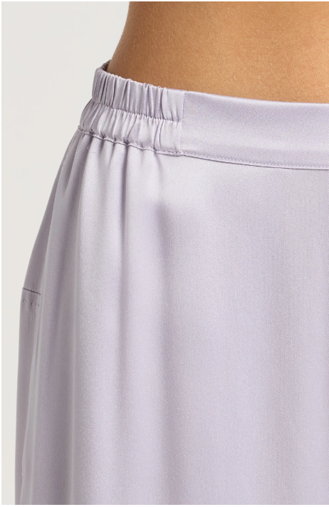 Pale lavender satin midi skirt with elasticated gathered waistband and smooth draped fabric shown on model's hip
