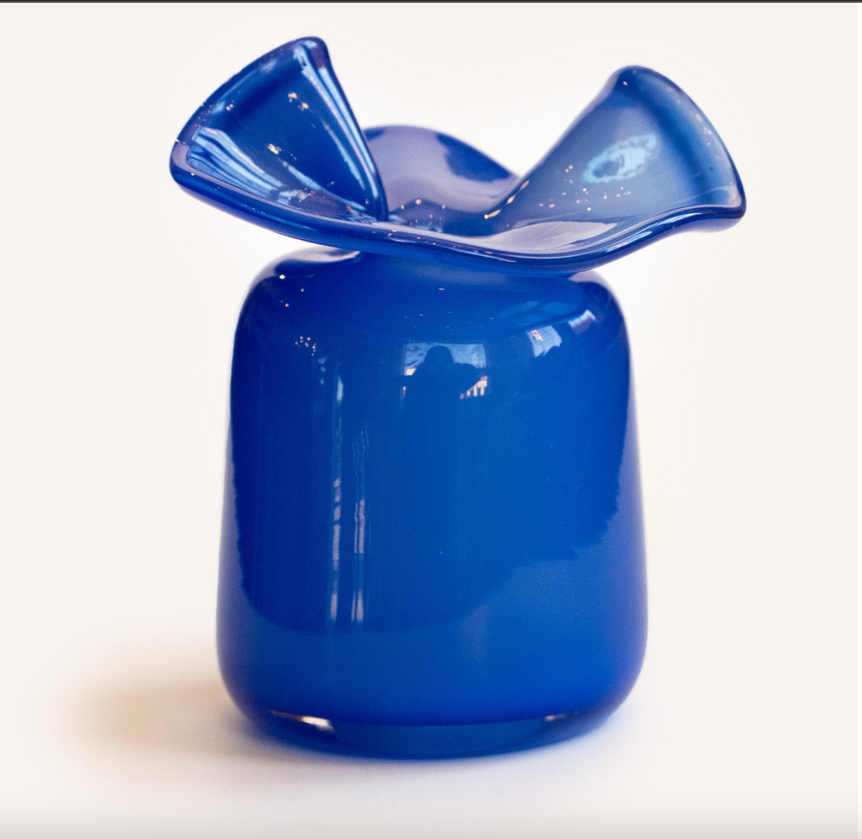 Cobalt blue blown glass vase with ruffled wavy rim and smooth rounded body with glossy translucent finish