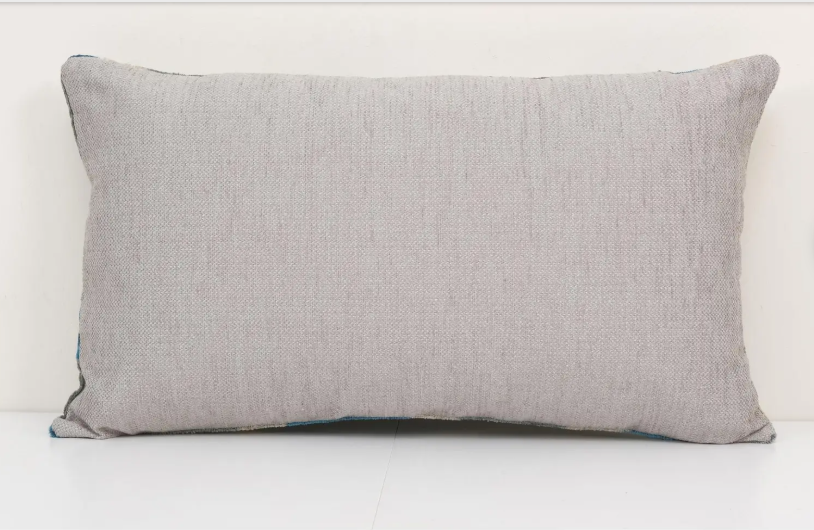 Rectangular lumbar pillow in heathered light gray linen with dark teal piped edges on white background