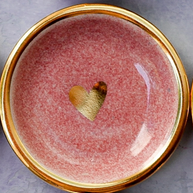 Pink ceramic trinket dish with speckled glaze finish, gold-rimmed edge, and metallic gold heart accent in center