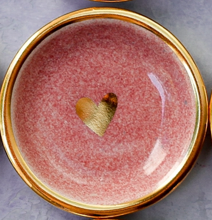 Pink ceramic trinket dish with speckled glaze finish, gold-rimmed edge, and metallic gold heart accent in center