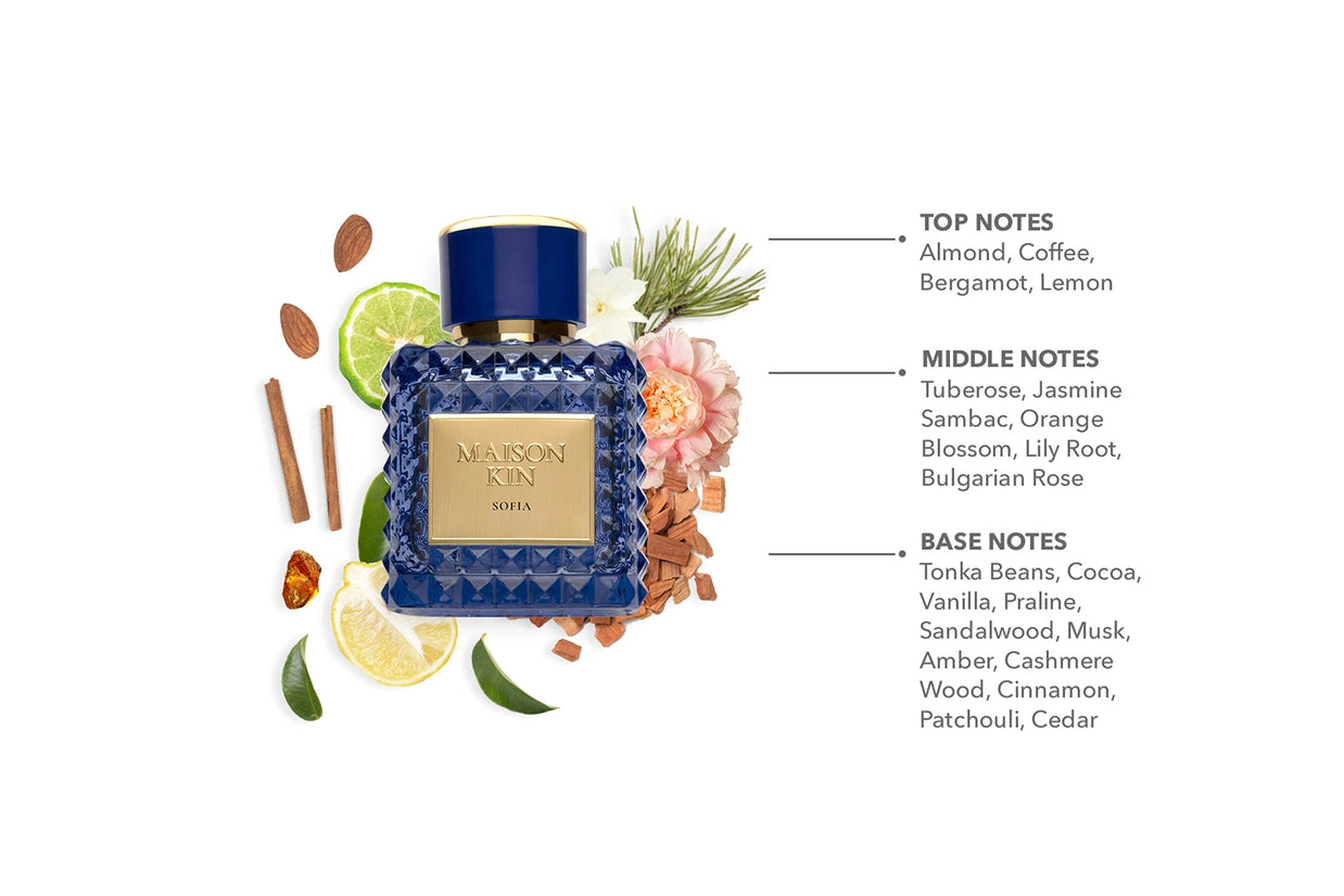 Maison Kin Sofia perfume bottle in navy blue cut glass with gold cap surrounded by citrus slices, flowers, and spice ingredients