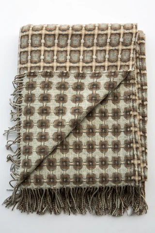Woven wool throw blanket in cream and brown geometric check pattern with knotted fringe trim folded on white background