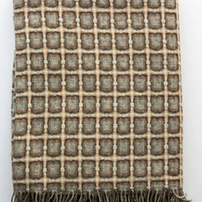 Woven wool throw blanket with geometric grid pattern in sage green, taupe, and cream with knotted fringe trim