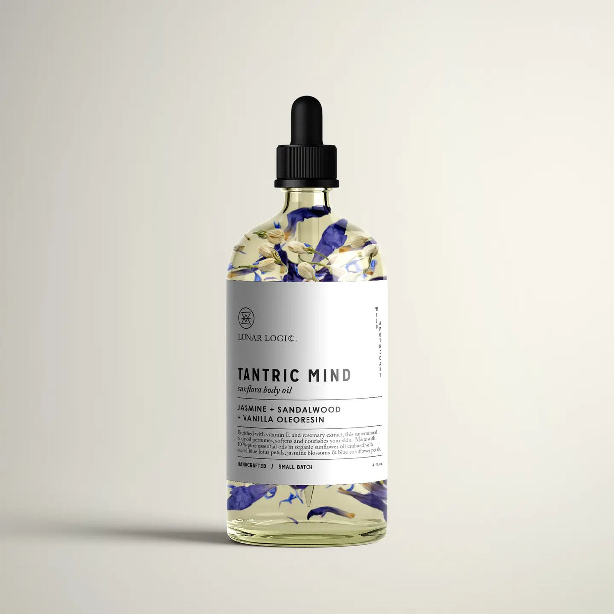 Clear glass dropper bottle with black cap filled with golden oil and purple flower petals, labeled Tantric Mind body oil