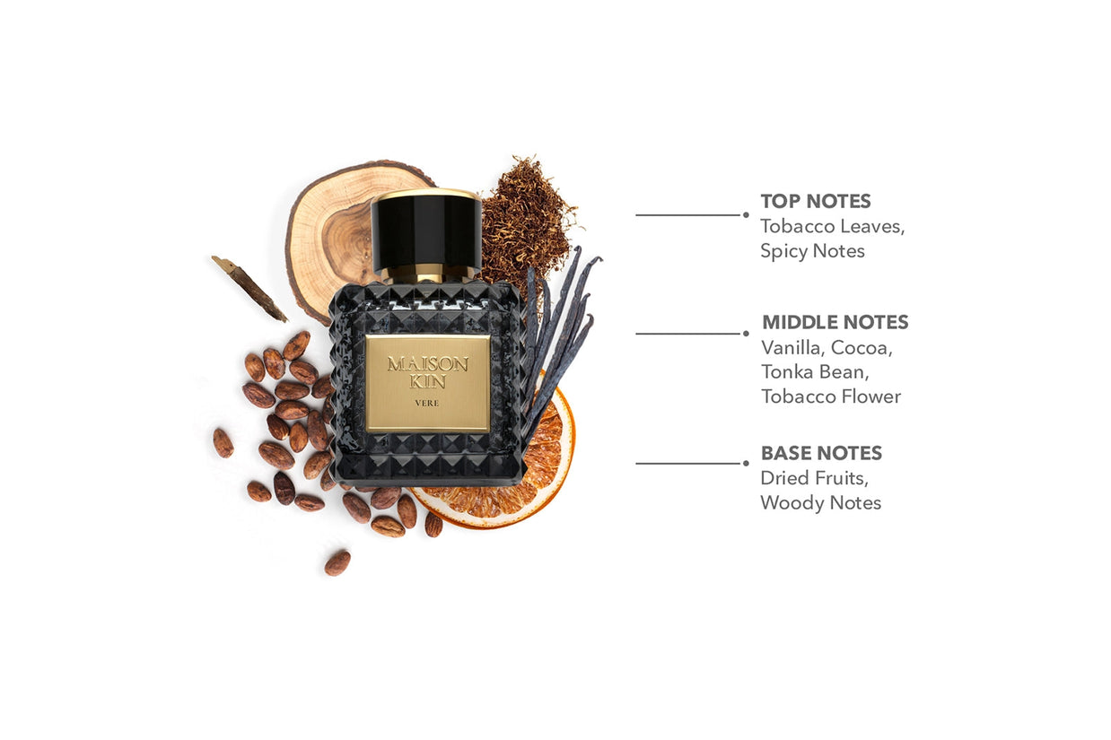 Maison Kin Vere perfume bottle with black geometric glass, gold label, surrounded by cocoa beans, tobacco, vanilla pods, wood slice
