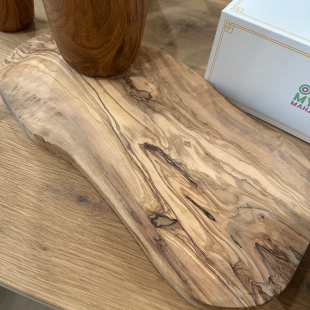 Oval olive wood serving board with rich marbled grain pattern and natural knots, displayed on light wood surface