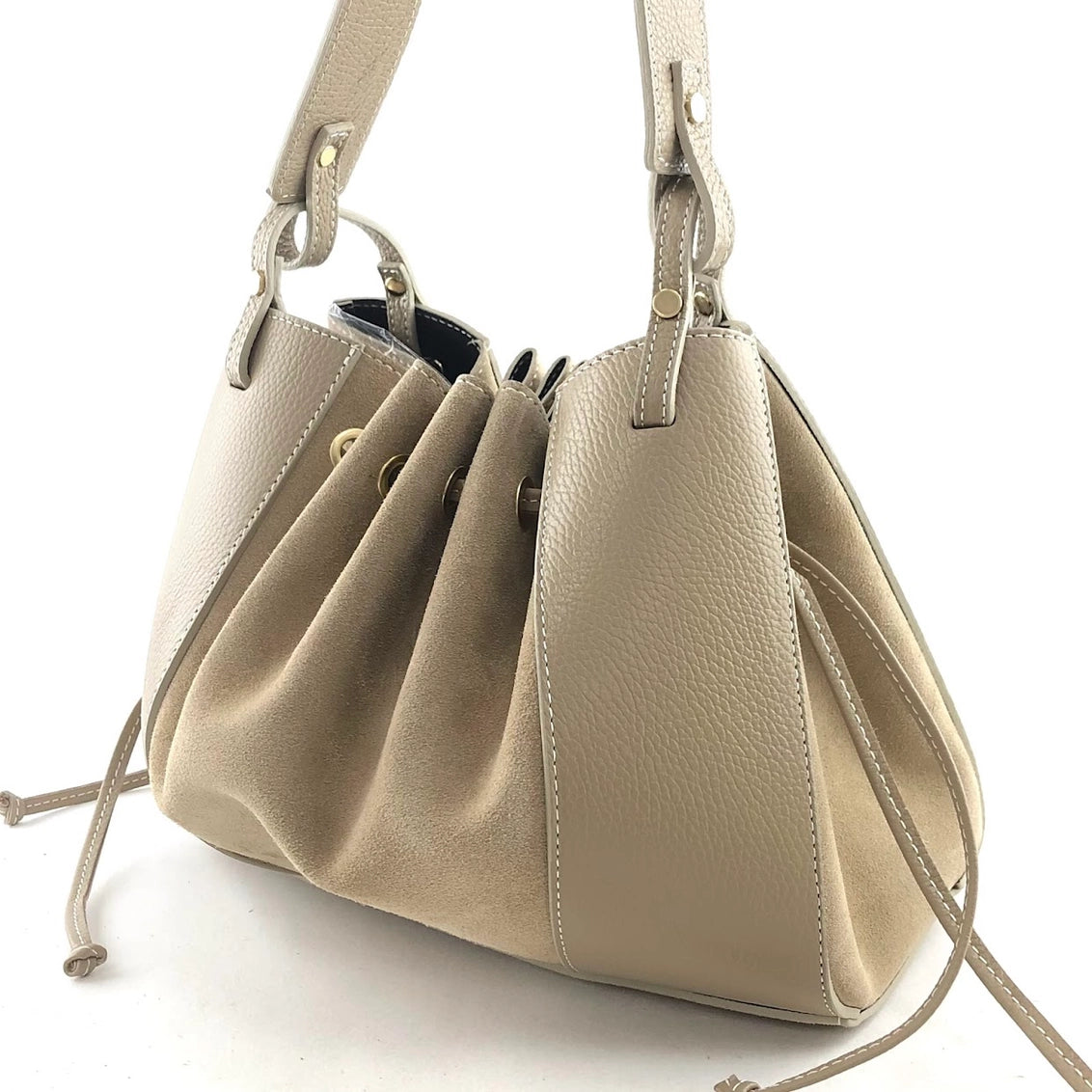 Taupe pebbled leather drawstring bucket bag with contrast stitching, structured base, and adjustable shoulder straps