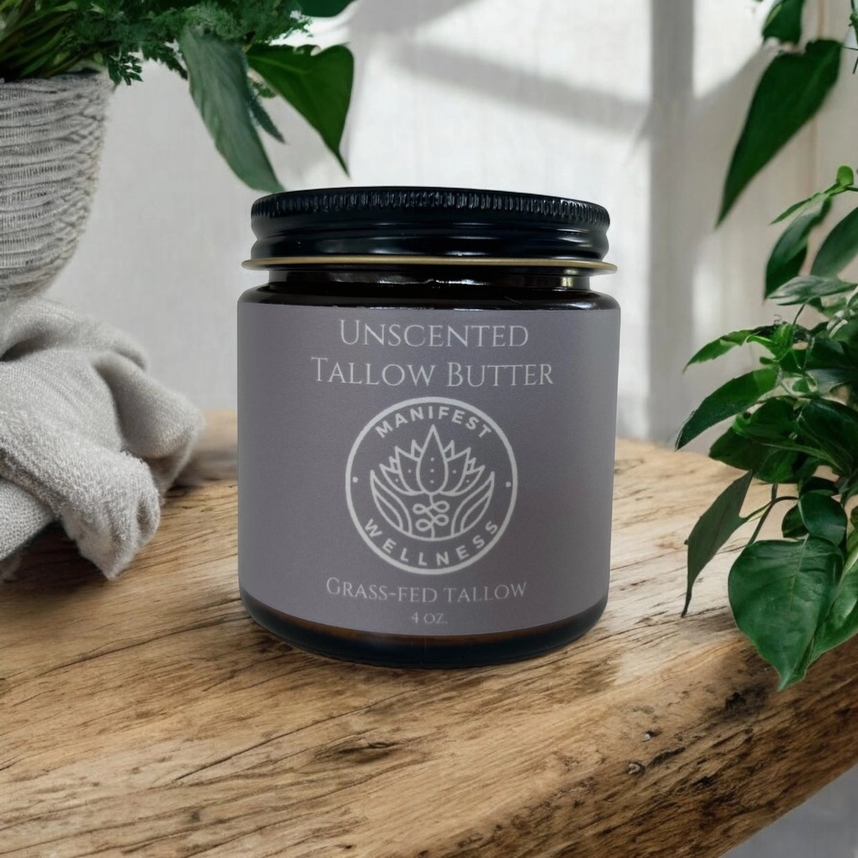 Dark amber glass jar with black metal lid containing unscented tallow butter, gray label with white lotus logo on wood surface