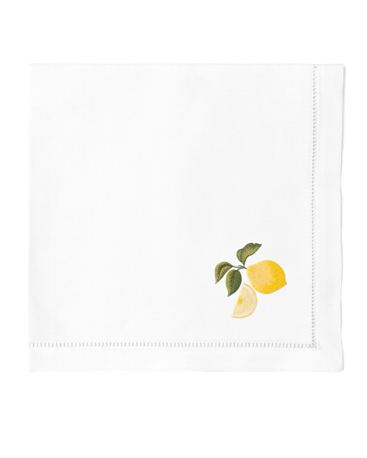 White linen napkin with hand-embroidered yellow lemons, green leaves, and lemon slice detail with decorative hemstitch border