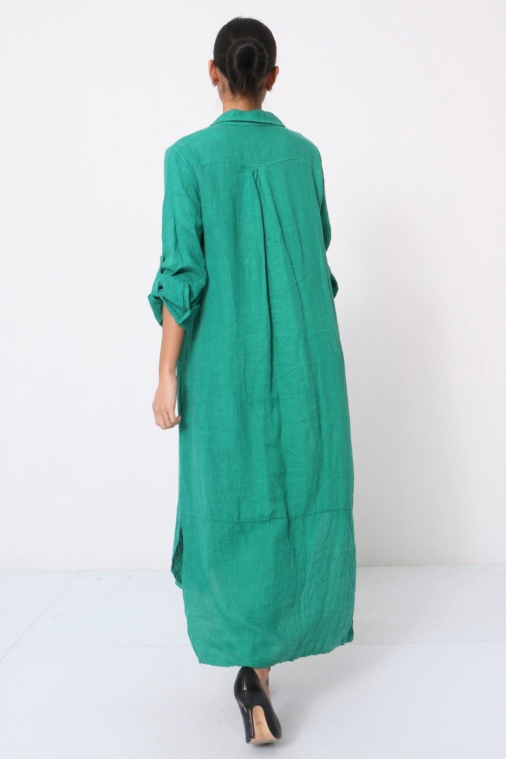 Back view of emerald green linen maxi shirt dress with collar, rolled sleeves, center pleat detail, and relaxed fit