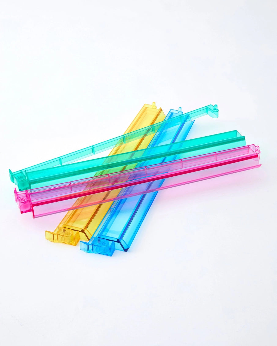 Translucent plastic bag clips in bright yellow, turquoise, blue, and pink with rectangular sliding closures stacked together