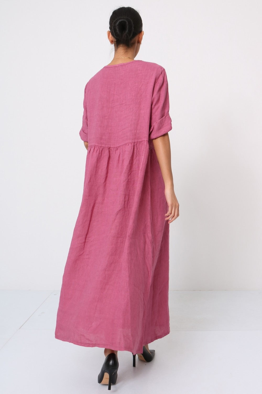 Rose pink linen maxi dress with empire waist, rolled short sleeves, and relaxed A-line silhouette shown from back