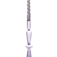 A tall, slender lavender purple glass candlestick holder with a twisted spiral taper candle inserted, set against a plain white background.