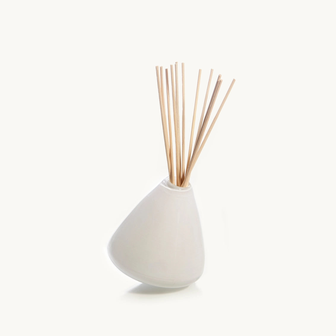 White frosted glass teardrop-shaped diffuser vessel with natural rattan reed sticks fanned at the top