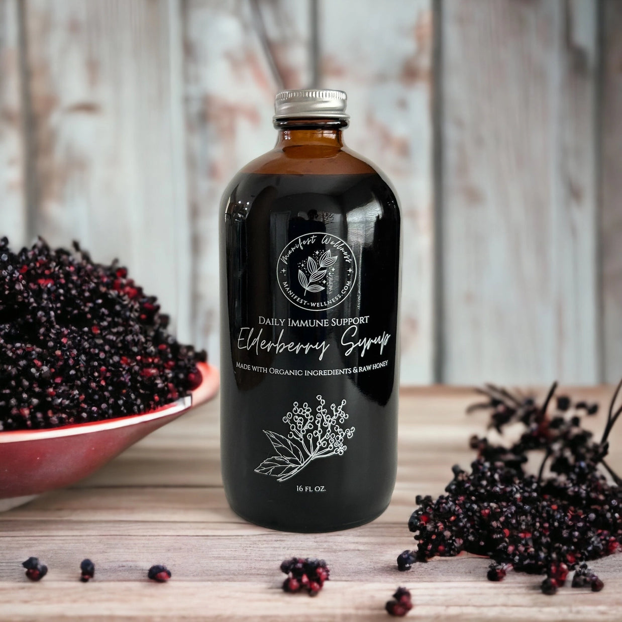 Bottle of elderberry syrup with a bowl of berries on a wooden surface