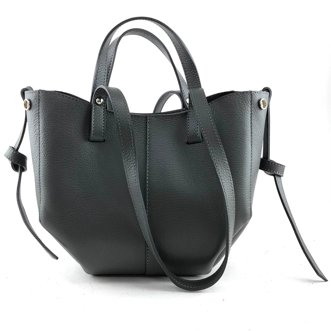 Slate gray pebbled leather tote bag with dual top handles, adjustable crossbody strap, and side tie details with gold hardware