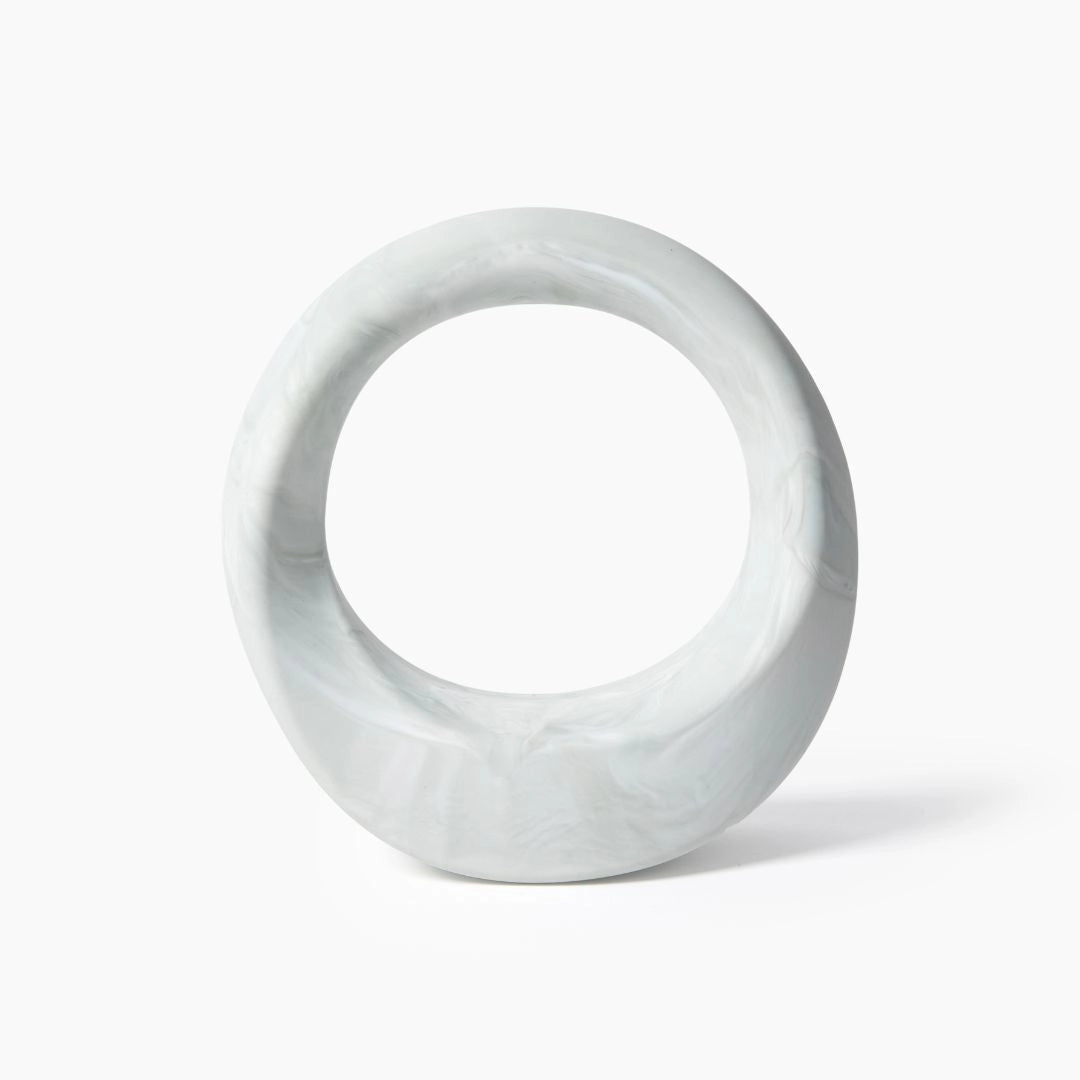 White marble circular sculpture with hollow center and natural gray veining throughout smooth polished surface