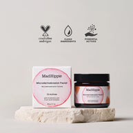 MadHippie microdermabrasion facial in amber glass jar with black lid and white box featuring pink circular design on stone