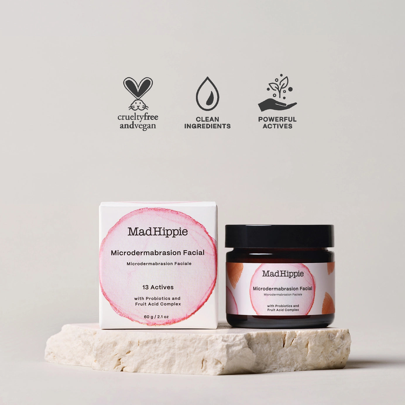 MadHippie microdermabrasion facial in amber glass jar with black lid and white box featuring pink circular design on stone