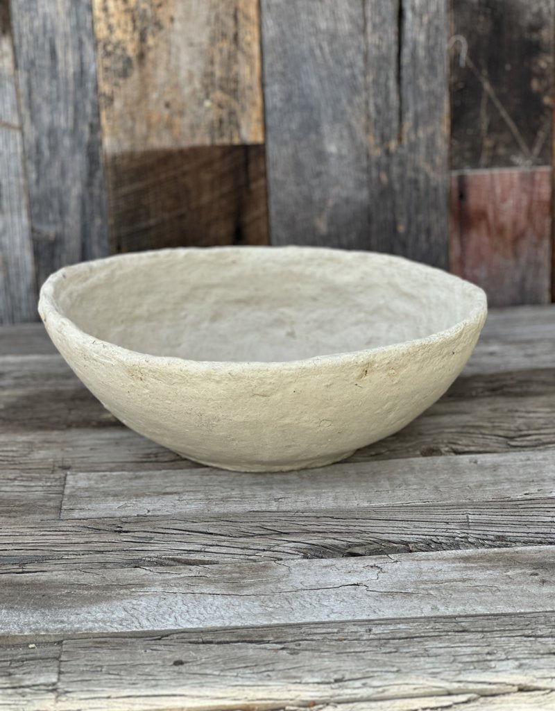 Cream-colored papier-mâché bowl with rustic textured finish on weathered wood surface against reclaimed barn wood backdrop