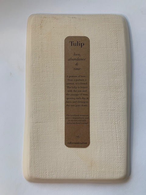 Natural cotton waffle-weave kitchen towel in cream with kraft paper bookmark label reading Tulip symbolism text