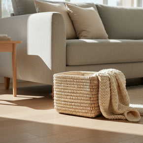 Handwoven rectangular basket in natural rattan with cream thread coil stitching creating horizontal striped pattern
