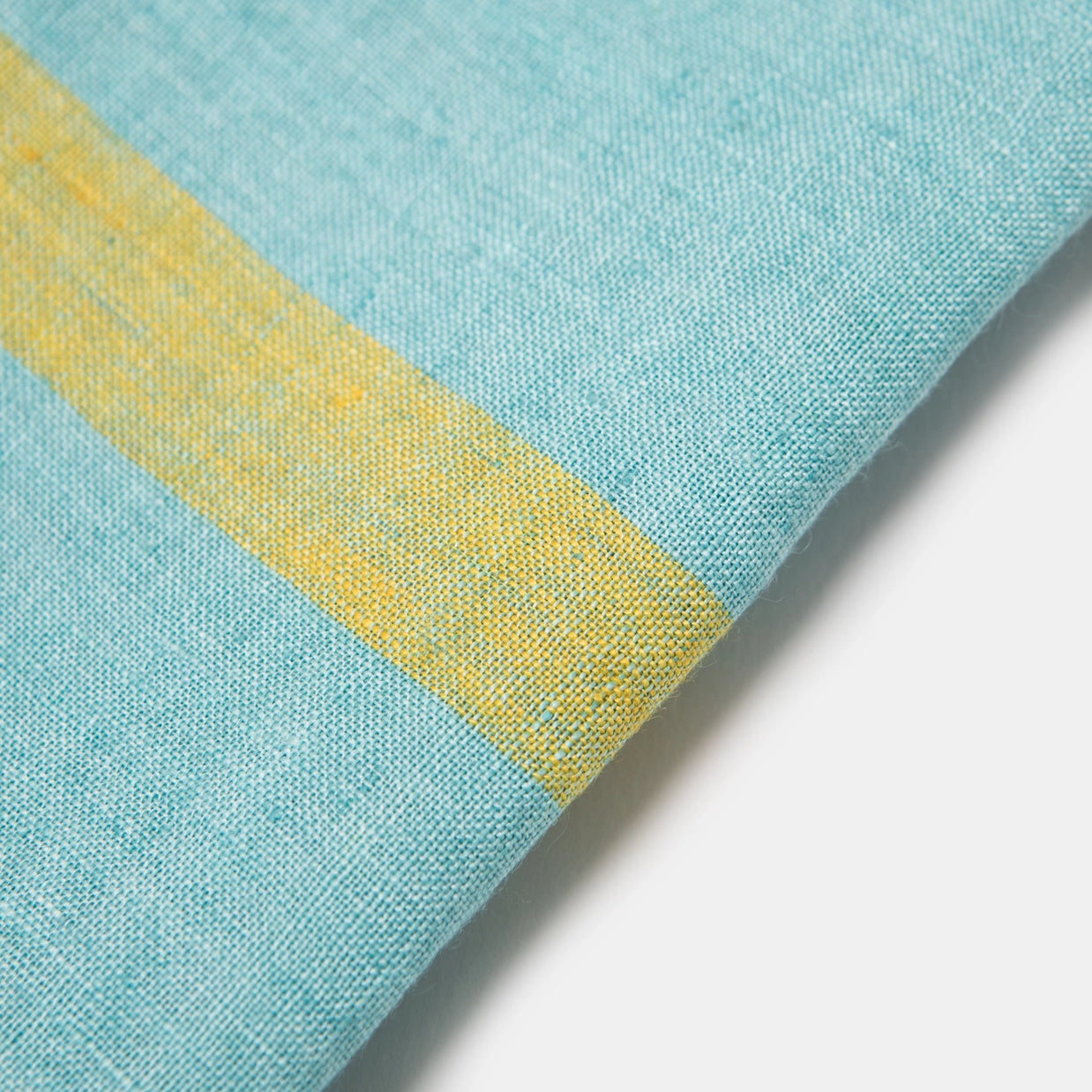 Aqua blue linen textile with diagonal golden yellow stripe showing detailed weave texture and folded corner edge