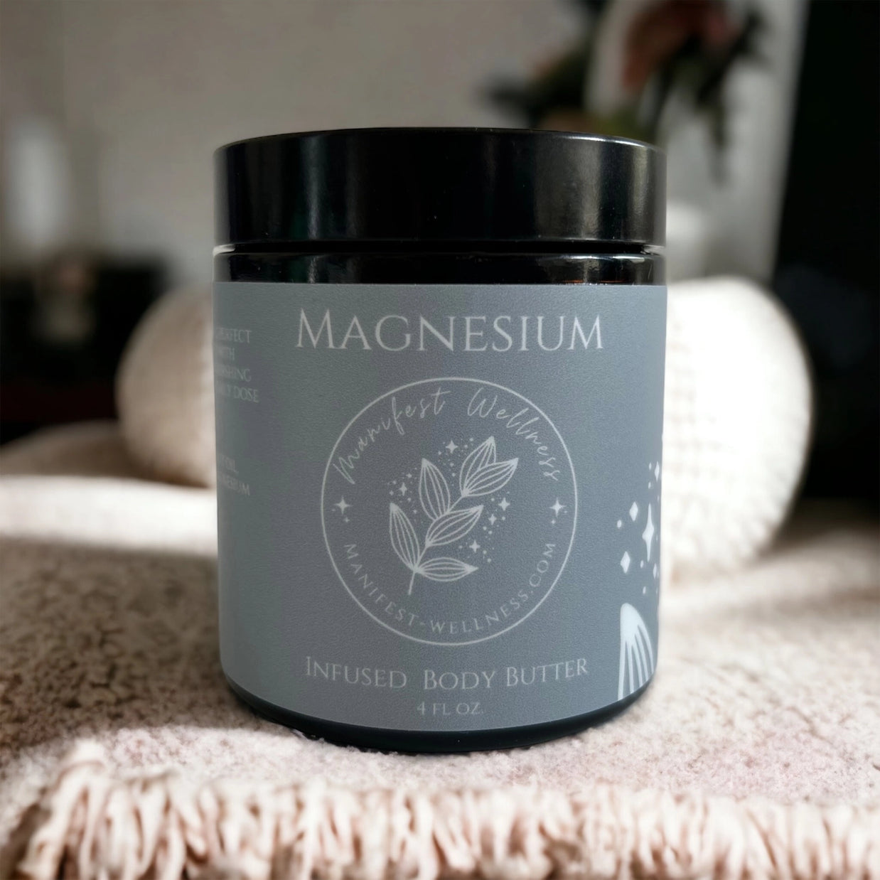 Dark amber glass jar with black lid and slate gray label reading Magnesium Infused Body Butter with botanical logo